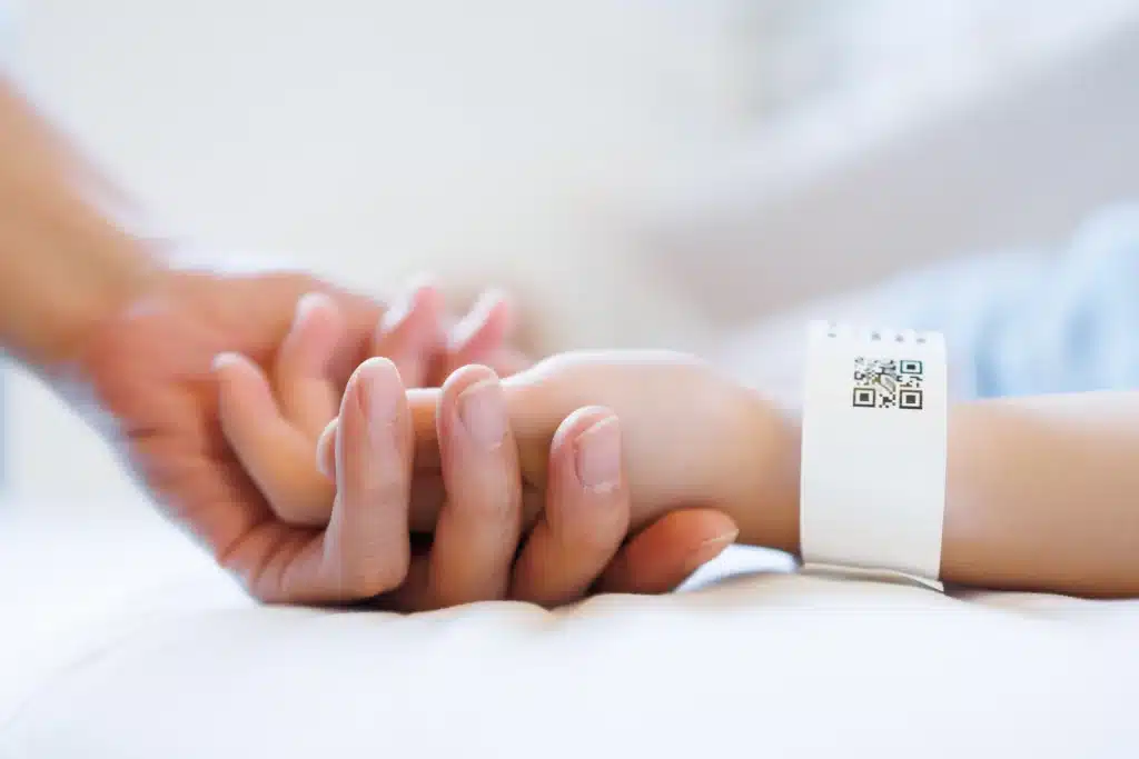 Close-up of patient wrist with barcode ID band, showing Chicago Tag & Label solutions for safe healthcare identification.