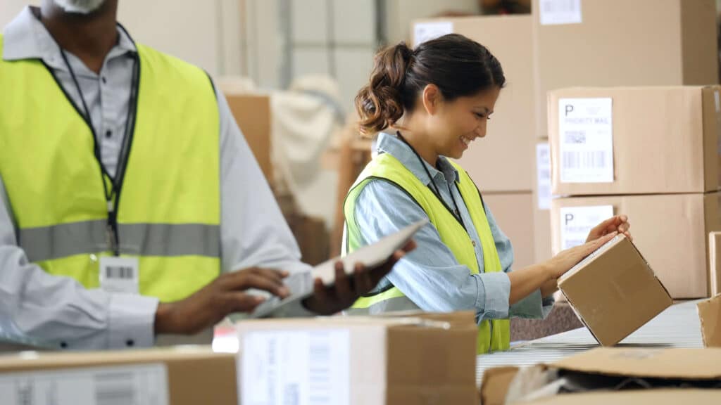 Happy woman at work in a warehouse lookiung at a shipping label